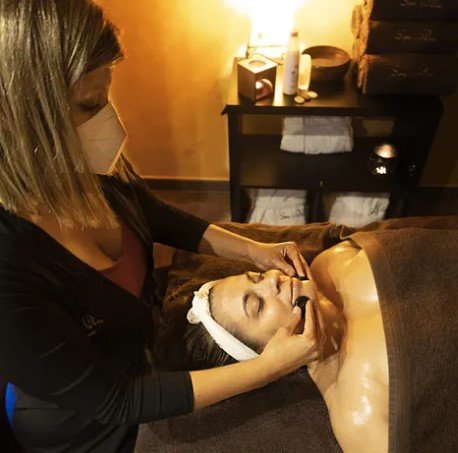 Una mujer que lleva una máscara le está dando un masaje a una mujer.