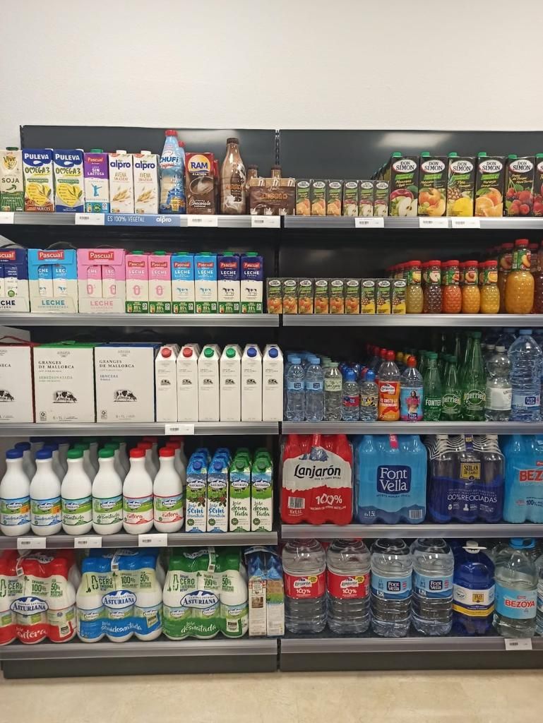 Un pasillo de una tienda de comestibles lleno de leche, jugo y agua.