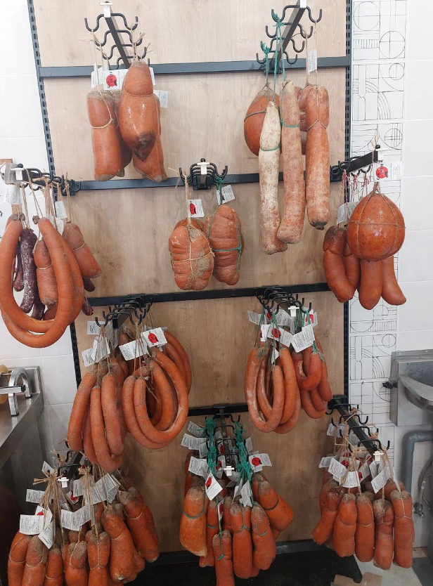 Un montón de salchichas están colgadas en una rejilla.