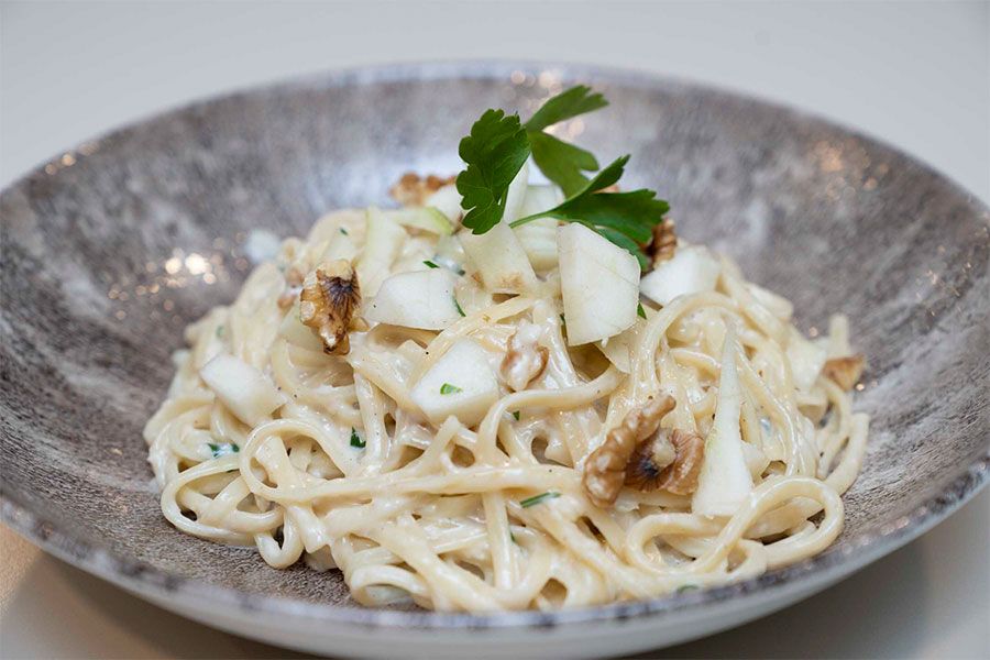 Un primer plano de un plato de pasta con verduras sobre una mesa.