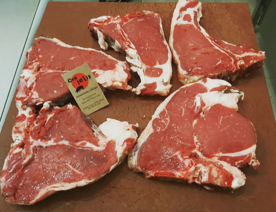 Varios trozos de carne cruda en una tabla de cortar con una tarjeta que dice