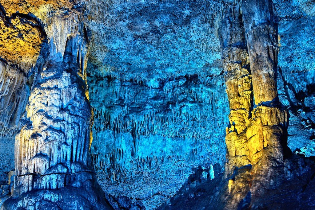 Una cueva azul y amarilla con muchas rocas y árboles.